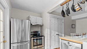 A modern kitchen with stainless steel appliances, wooden flooring, and white cabinetry. - House Patrick  4Bd Loft Style Parking (St. John's)