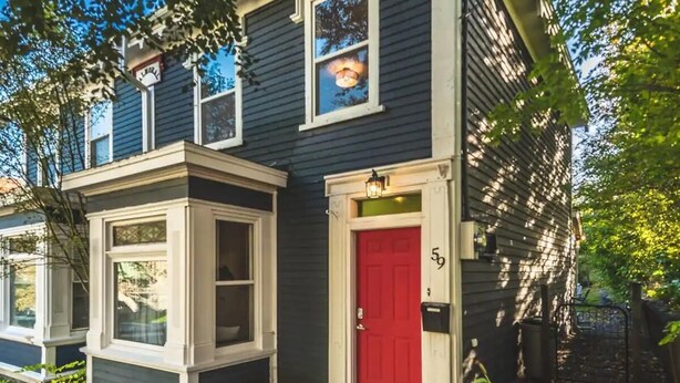 A two-story house with a red door and a small porch with a window. - House Patrick  4Bd Loft Style Parking (St. John's)