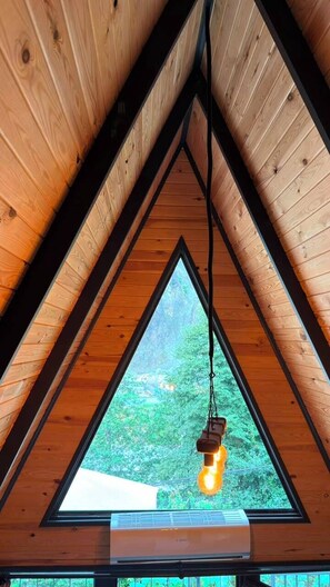 A triangular wooden ceiling with a hanging light fixture and an air conditioning unit below it. - La Vica Bungalow (Camlihemsin)