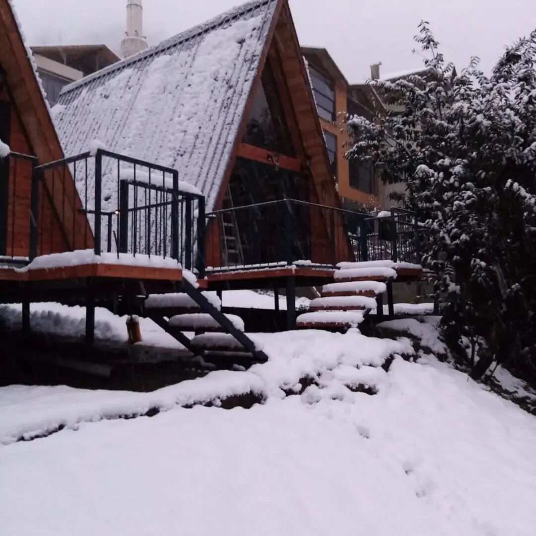 Una hilera de cabañas de madera con techos nevados y escalones.