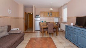 Un espacio habitable compacto con kitchenette, comedor y zona de estar.