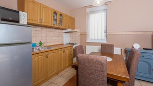 Una cocina compacta con armarios de madera, microondas integrado, estufa a gas y una mesa de comedor con sillas.