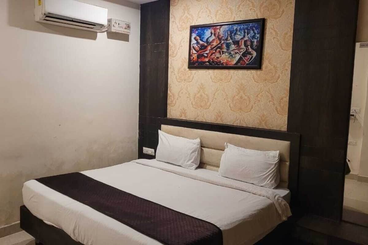 Una habitació d'hotel amb un llit, un quadre a la paret i un aparell d'aire condicionat.