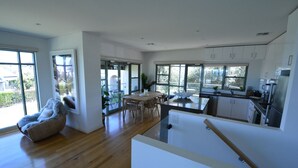 A modern kitchen with white cabinets, a dining area with a wooden table and chairs, and a large window providing natural light. - Bayview Apartment Sorrento, a family-friendly haven 350 meters from the beach.   (Sorrento)