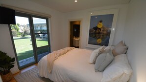A bedroom with a large bed, a bedside table, a lamp, a window, and a door leading to a balcony. - Bayview Apartment Sorrento, a family-friendly haven 350 meters from the beach.   (Sorrento)