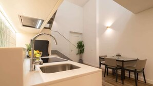 Una cocina moderna con un lavamanos doble, un grifo de acero inoxidable y un pequeño comedor con una mesa y sillas.