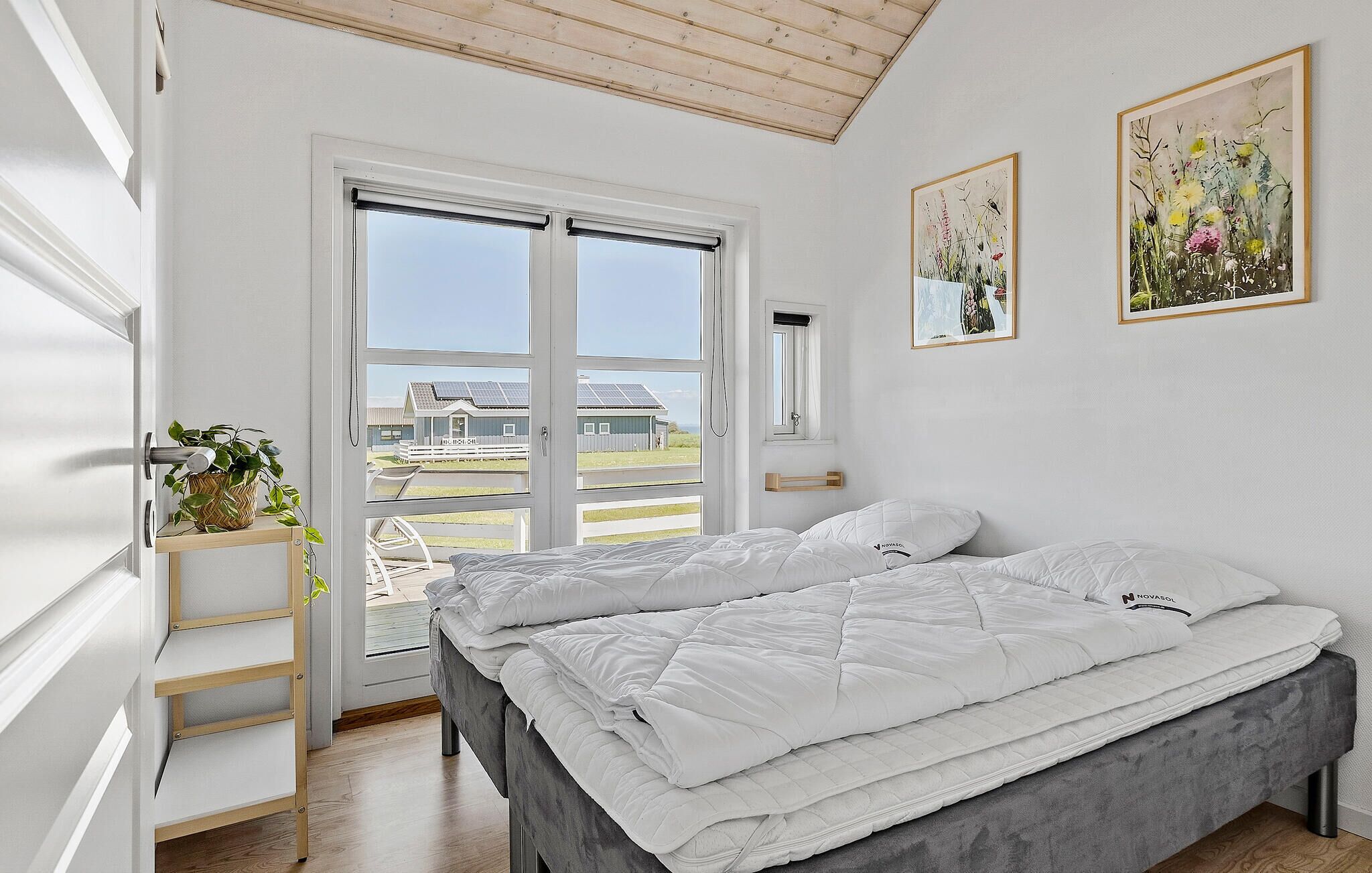 A bedroom with a bed, a window, and two framed pictures on the wall.