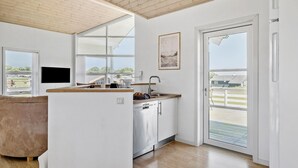 A modern kitchen with a wooden ceiling, large windows, and a view of the outdoors.