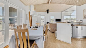 A modern kitchen with a central island, wooden flooring, and large windows providing natural light.