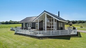 A modern house with a large deck, a chimney, and a view of the surrounding landscape.