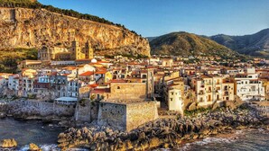 A coastal town with historic buildings, a prominent church, and a rocky shoreline. - Rome Suite. Within walking distance of the sea, and the heart of beautiful Cefalù.  (Cefalù)