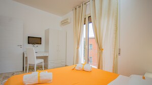 A hotel room with a bed, a desk, and a television. - Rome Suite. Within walking distance of the sea, and the heart of beautiful Cefalù.  (Cefalù)