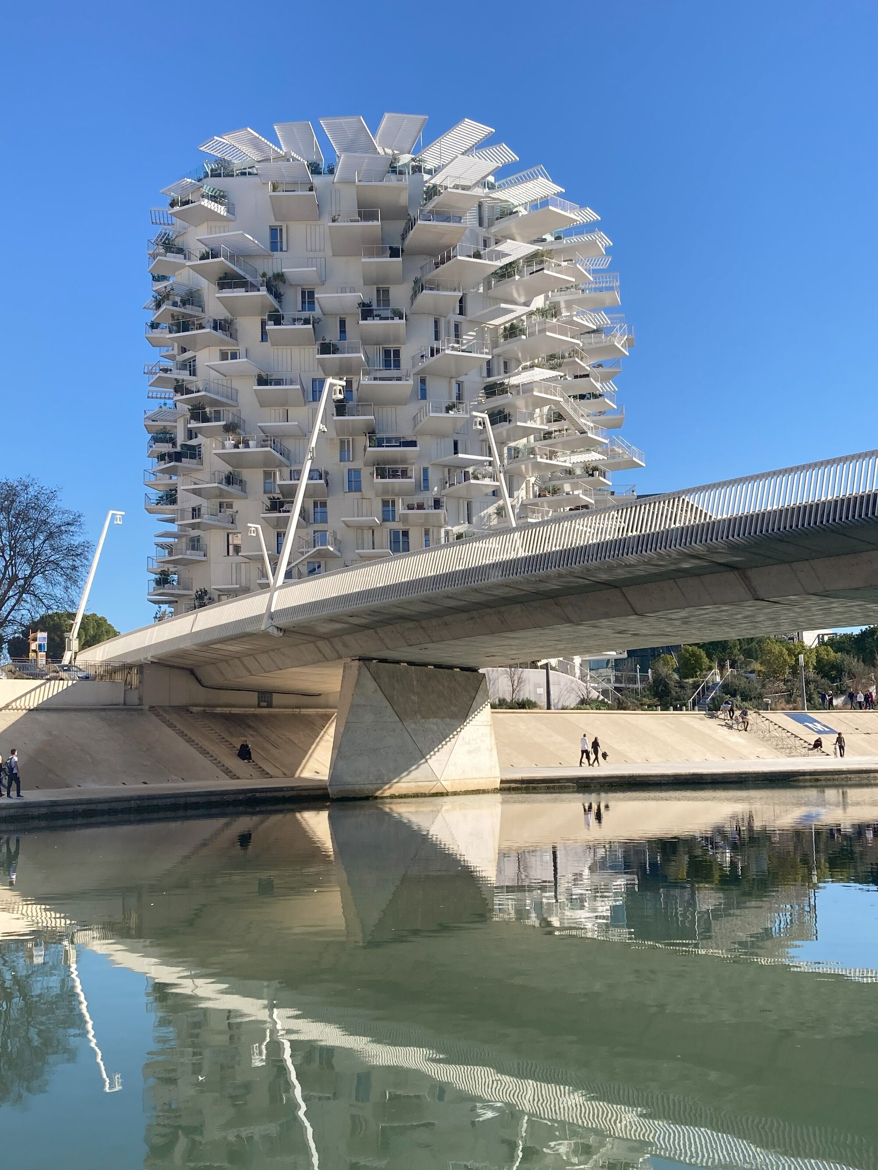 A modern building with balconies and a bridge over a body of water.
