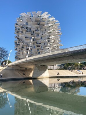 Un edificio moderno con balcones y un puente sobre el agua.