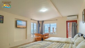 Un dormitorio con dos camas, televisión, ventana con vistas y una silla.