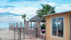 Una propiedad frente a la playa con una estructura de techo de paja, un patio cercado y vista al océano.