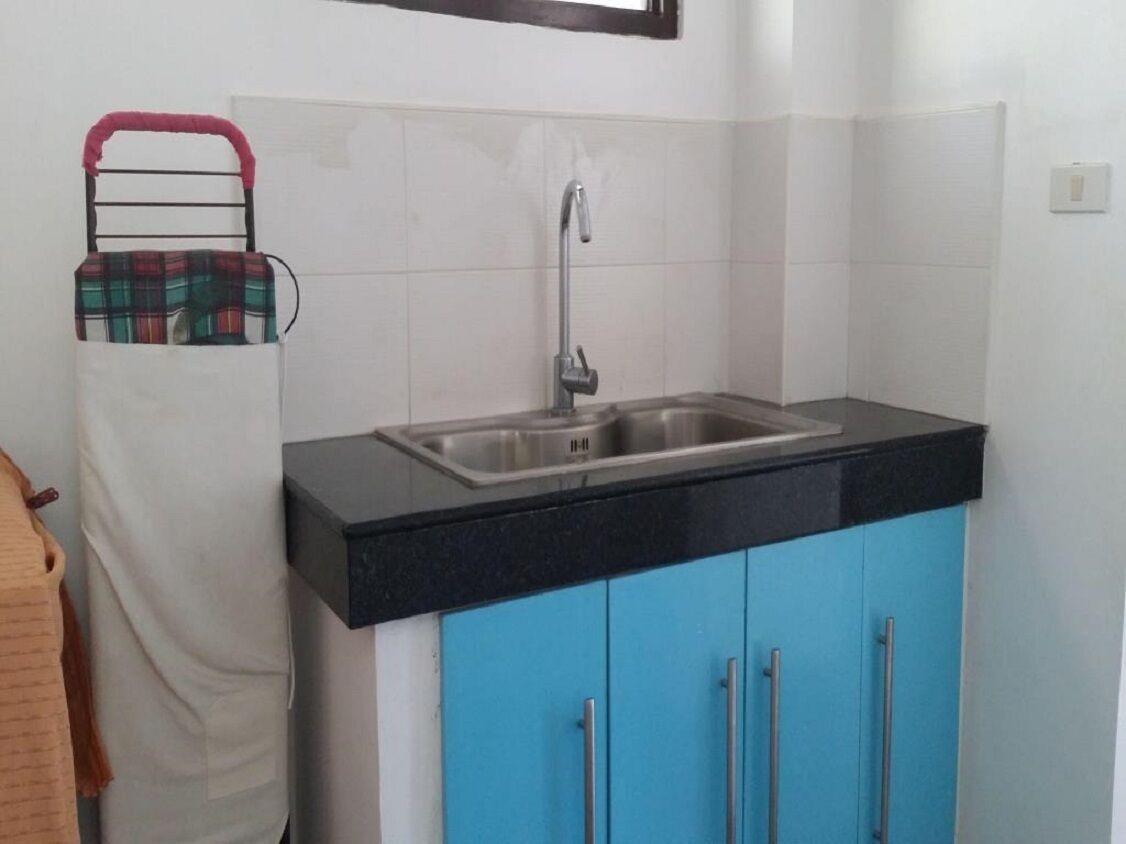 Una cocina con encimera negra, pileta de acero inoxidable y alacenas azules.