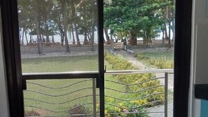 A view through a door with a metal mesh screen, leading to an outdoor area with trees and a pathway. - Villa del Nico


 (Pagudpud)