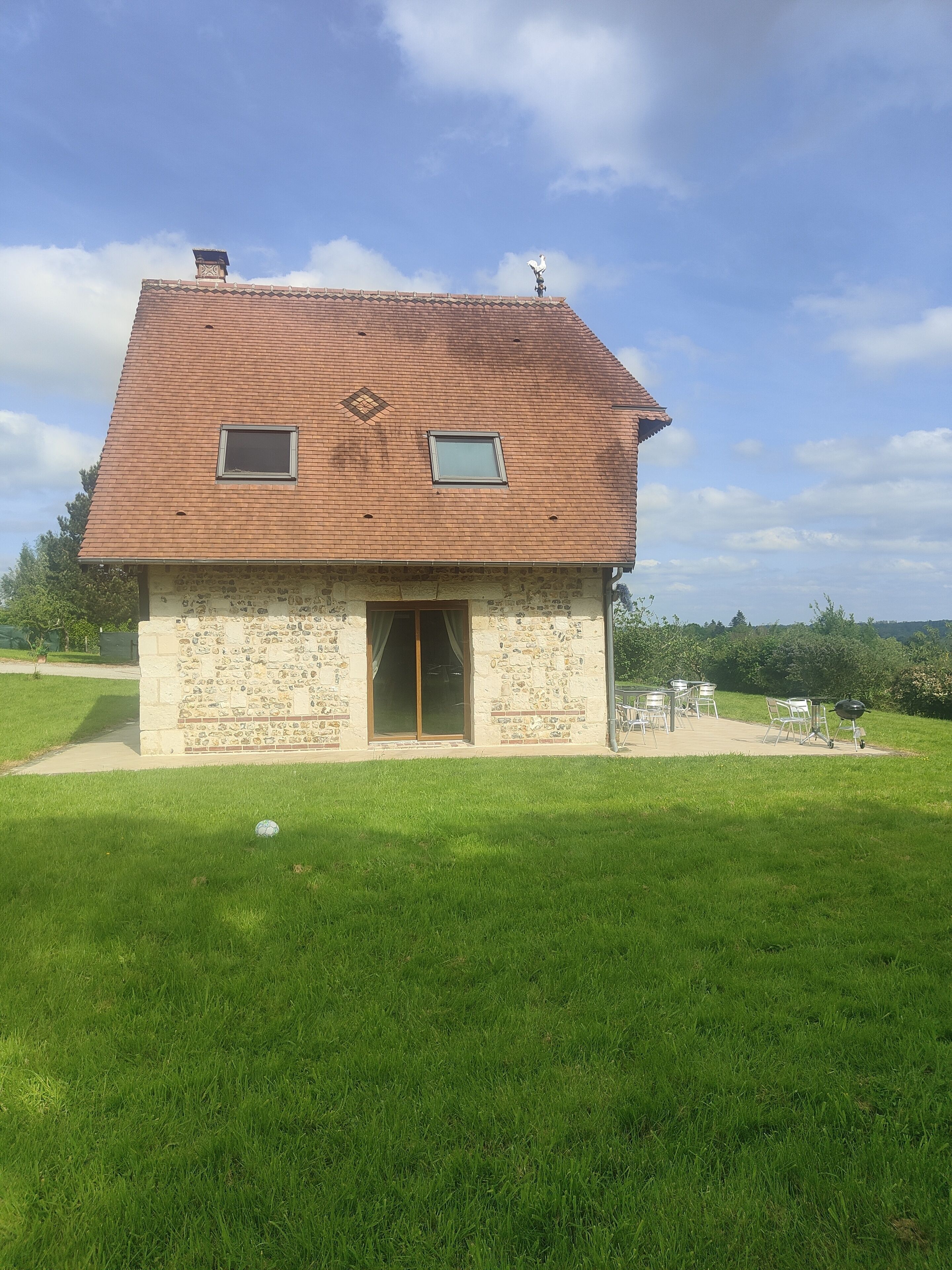 A two-story stone house with a tiled roof, a small window, and a door.