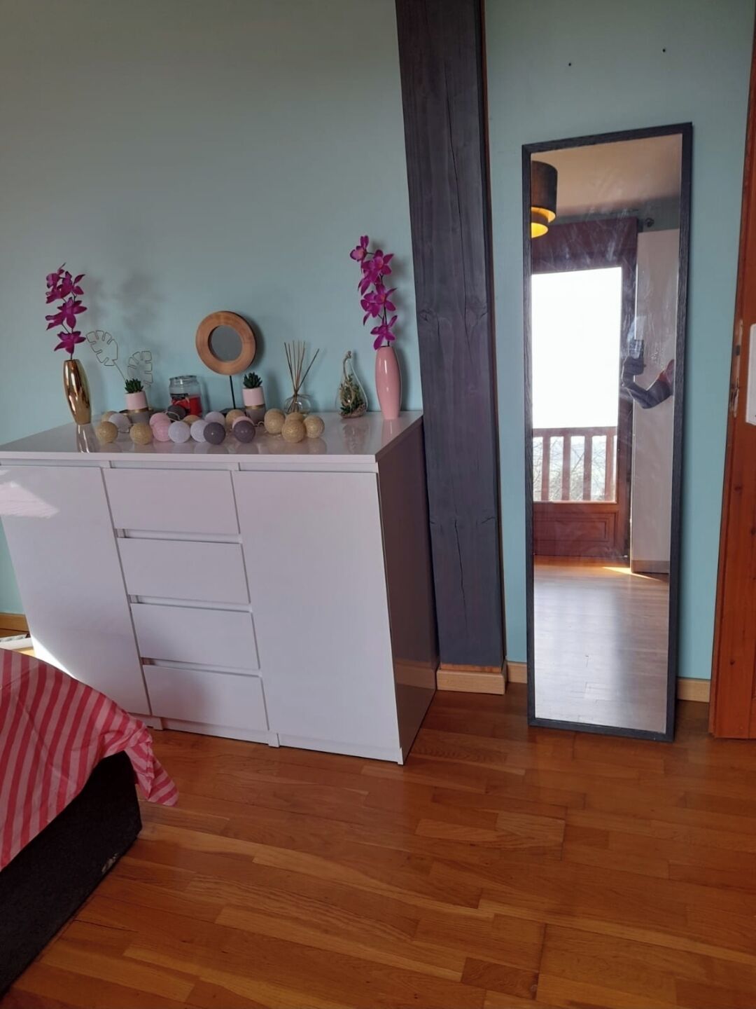 Ein Zimmer mit einem weißen Schminktisch, einem Spiegel und einem Holzboden.