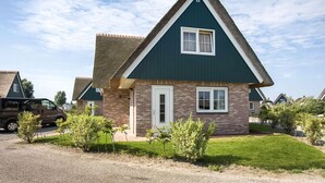 A two-story house with a steeply pitched roof, a brick facade, and a small front porch.