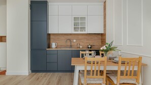 A modern kitchen with white and dark grey cabinets, a wooden countertop, and a dining area with a wooden table and chairs.
