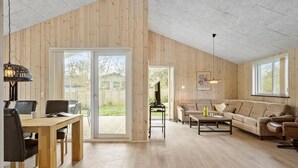 Un amplio espacio de sala con piso de madera, un sofá, una mesita de centro y un televisor.