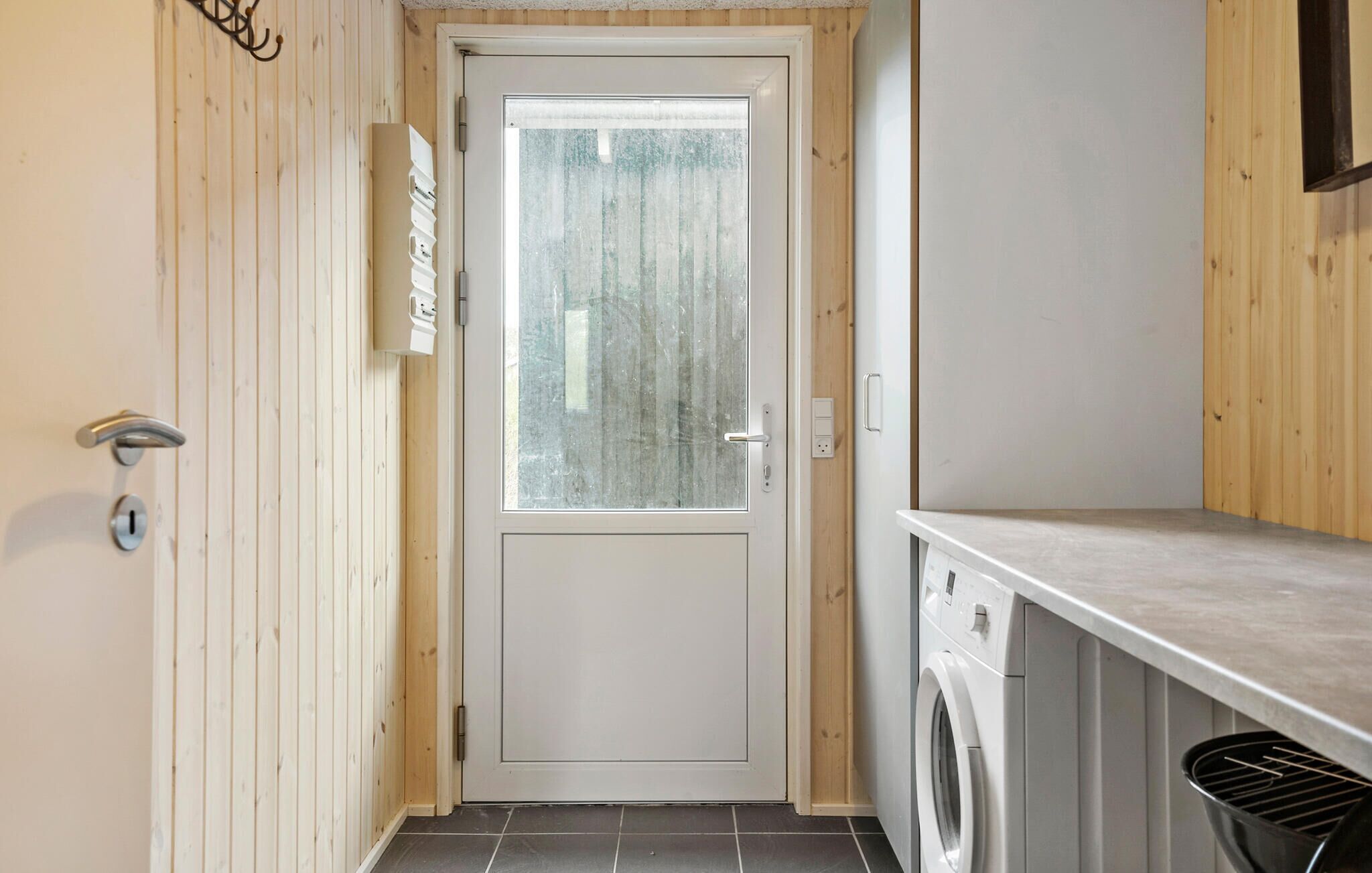 Un espace buanderie comprenant un lave-linge, un sèche-linge et une porte en verre dépoli.