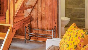A wooden staircase, a metal drying rack, a white toilet, and a yellow floral bedspread.