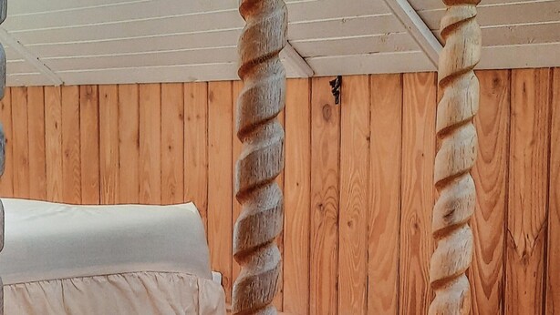 A room with wooden walls and a bed with a white sheet.