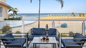 Un balcon doté d’un espace salon donnant sur une plage, avec une table sur laquelle sont disposés un narguilé et des objets décoratifs.