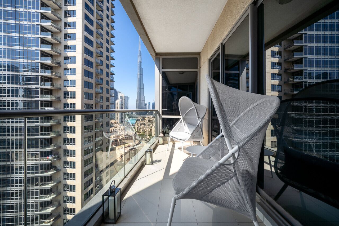 Ein Balkon mit Blick auf ein hohes Gebäude, einem Stuhl und einem Tisch.