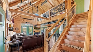 Un interior de madera con una escalera, un sofá y un televisor.