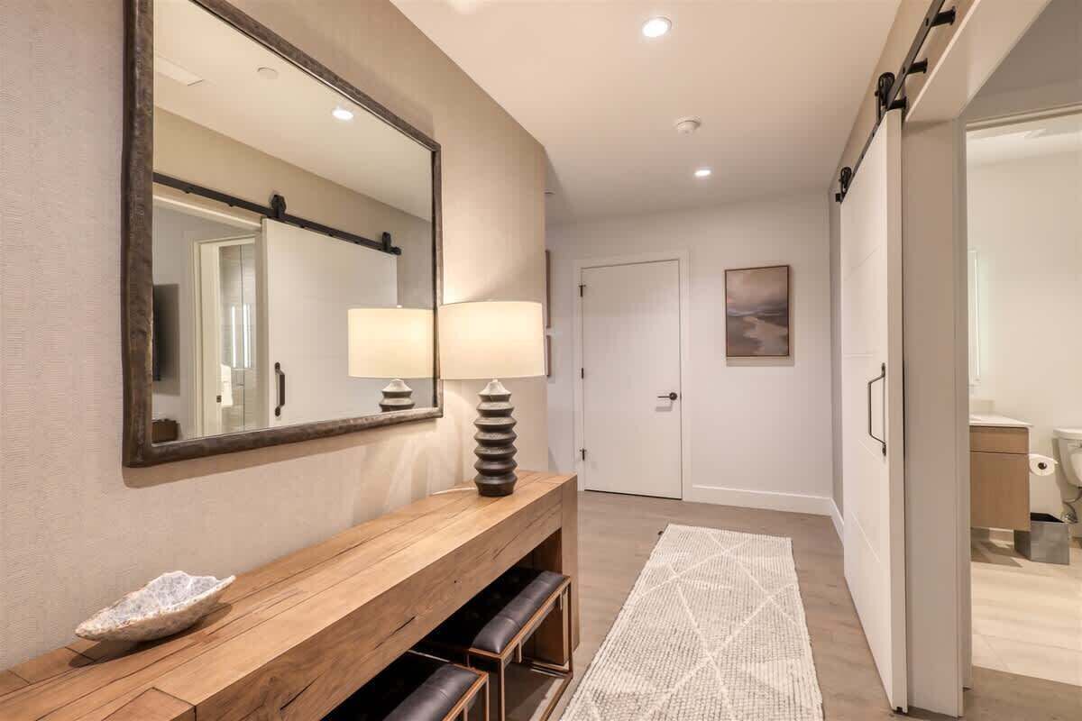 Une salle de bain moderne avec un grand miroir, un meuble-lavabo en bois, un lavabo et des toilettes.