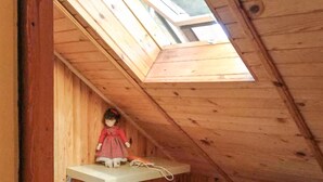 Una muñeca sobre una estantería en un ático de madera con tragaluces.