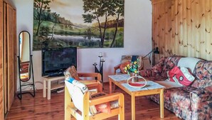 Una sala de estar acogedora con piso de madera, un sofá, una mesa de centro y un cuadro de un paisaje en la pared.