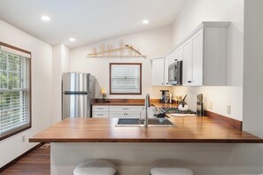 Een moderne keuken met een houten aanrecht, roestvrijstalen apparatuur en witte kastjes.