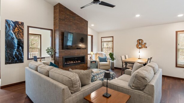 Una sala de estar moderna con chimenea, ventilador de techo y comedor con mesa y sillas.