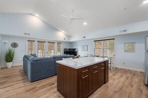 A spacious kitchen with a marble island, wooden cabinets, and a built-in TV. - Explore, Relax, Repeat — Cozy Condo Between Petoskey & Harbor Springs (Harbor Springs)