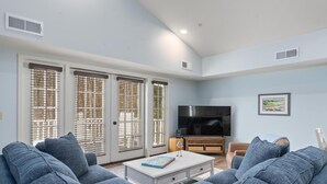 Un salon avec un canapé, une table basse, un téléviseur et un tableau encadré au mur.