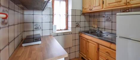 A compact kitchen with a wooden countertop, a built-in stove, a sink, and wooden cabinets.