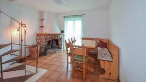 Une pièce chaleureuse avec une cheminée, un banc en bois, une table à manger et un escalier.