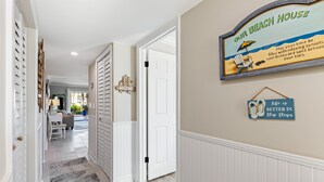 A hallway with a 'Welcome' sign, a beach-themed sign, and a 'Life is better in flip flops' sign.
