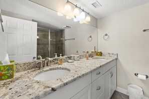 A bathroom with two sinks, a large mirror, and a shower. - Beautifully Updated Ground Floor Condo Stops From The Pool And Beach Access! (St. Augustine)