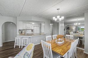 Una cocina moderna con armarios blancos, una mesa de comedor de madera y taburetes blancos.