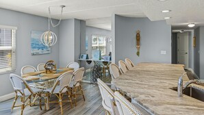 A dining area with a large marble table, wicker chairs, and a hanging light fixture. - Ground Floor Oceanfront Condo With Beach Access At Your Back Door! (St. Augustine)