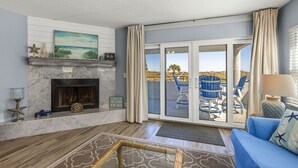 A living room with a fireplace, a sofa, and a view of the outdoor patio. - Ground Floor Oceanfront Condo With Beach Access At Your Back Door! (St. Augustine)