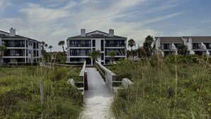 A pathway leading to a modern multi-story building with balconies, surrounded by natural vegetation. - The best Views On The Beach From This 3rd Floor Oasis!! (St. Augustine)