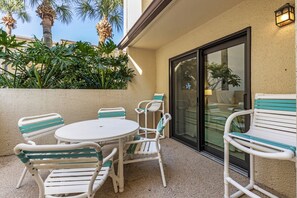 Une terrasse avec une table ronde et quatre chaises, une porte-fenêtre coulissante et un petit espace extérieur agrémenté de plantes.