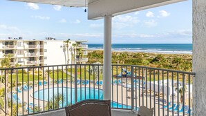 A balcony with a pool, lounge chairs, and a view of the ocean and resort buildings. - Stunning views from this top floor three bedroom condo! (Saint Augustine)